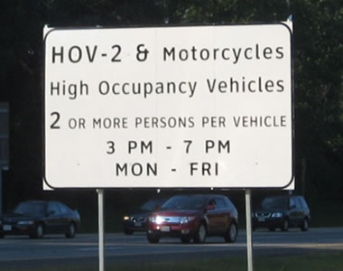 An image of a rectangular regulatory sign for high-occupancy vehicles. The legend is displayed in upper- and lower-case letters of the alternative alphabet.