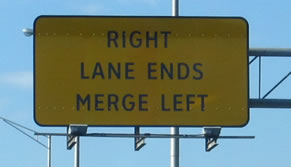 The photograph at center right is a rectangular warning sign that displays the legend "RIGHT LANE ENDS MERGE LEFT" in the alternative alphabet in a negative-contrast orientation.