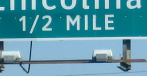 An image of a guide sign distance legend of "½ MILE" is shown. The numerals and solidus of the fraction are aligned as a single line instead of the numerals being arranged diagonally about the solidus.